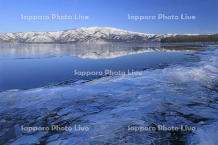 屈斜路湖の岸に寄せられた氷と藻琴山