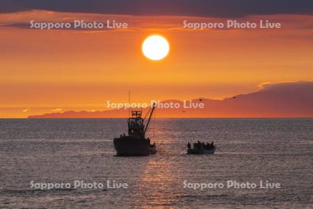 オホーツク海の日の出と知床連山と漁船