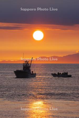 オホーツク海の日の出と知床連山と漁船