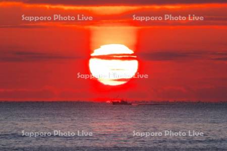 日の出（サンピラー）と朝の海と漁船
