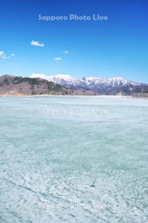 氷の残るシューパロ湖と夕張山地