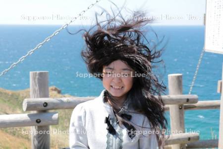 強風の積丹岬の女の子